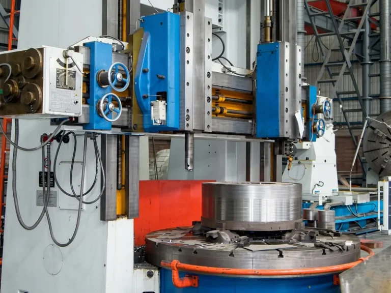 Heavy-duty CNC vertical turning lathe performing precision machining on a large diameter metallurgical component in the DURON manufacturing facility.